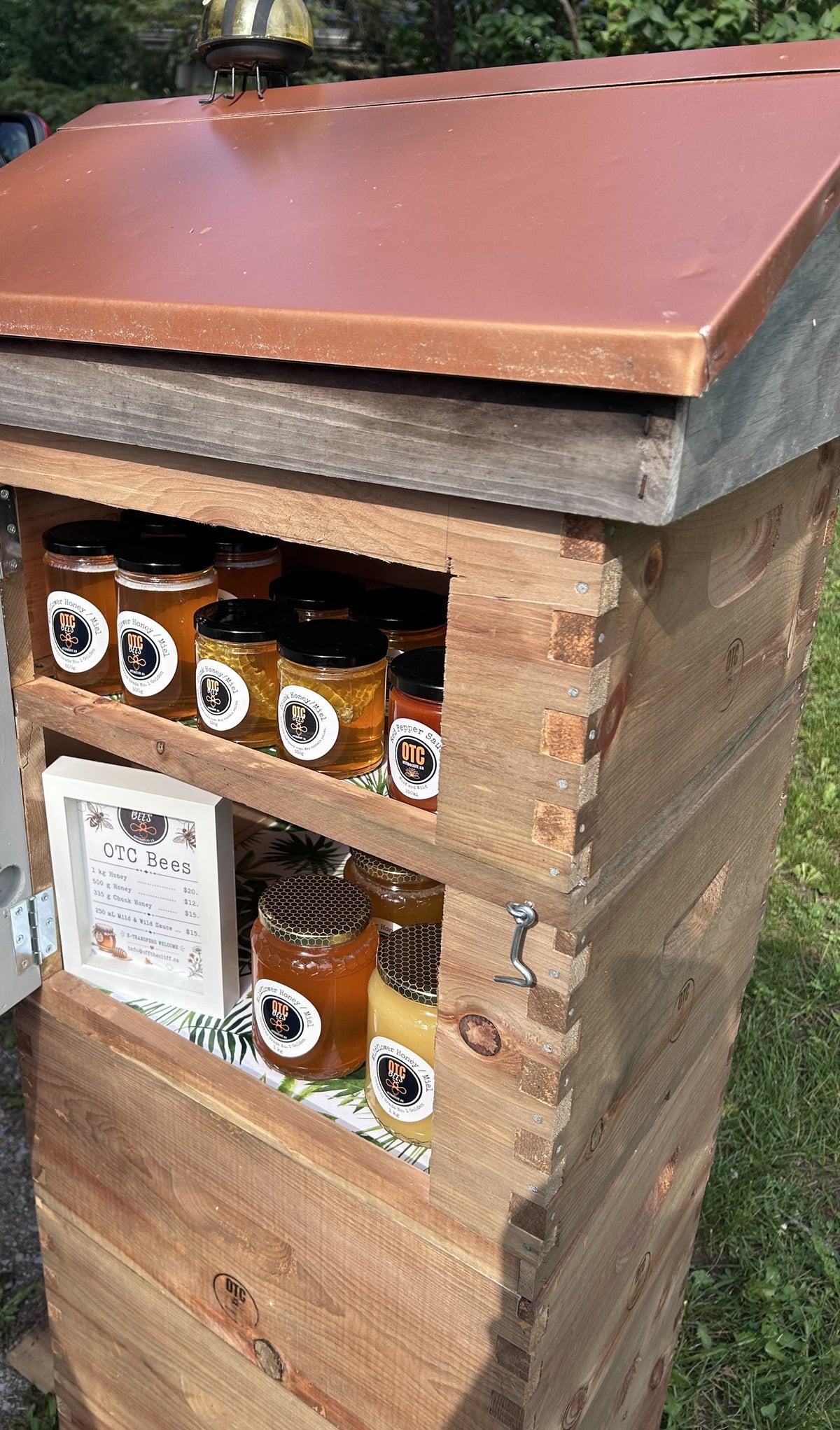Off The Cliff roadside honey stand built from beehive boxes, stocked with wildflower honey, chunk honey and Mild & Wild sauce